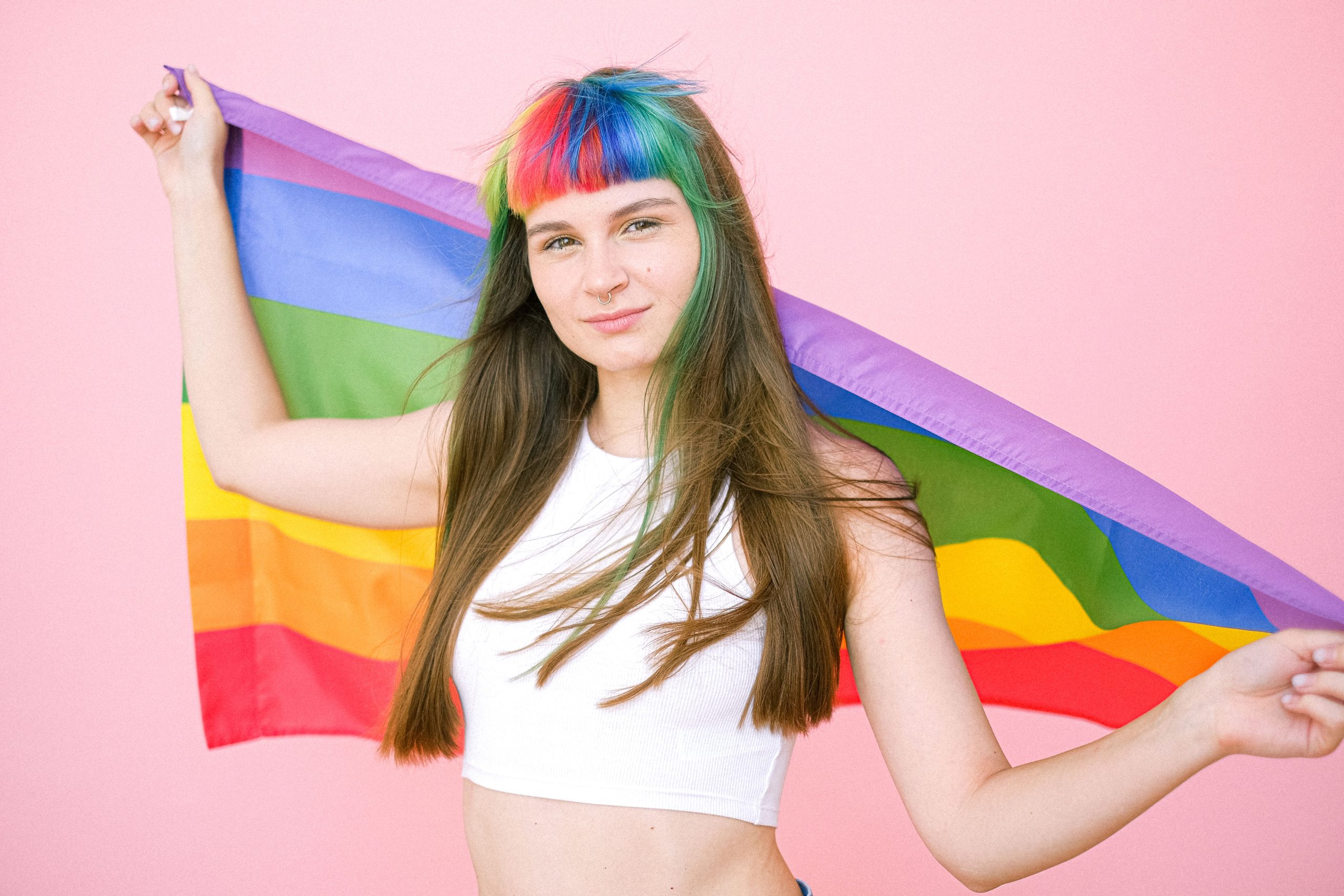Young adult holding a Pride flag for gender-affirming voice and communication support